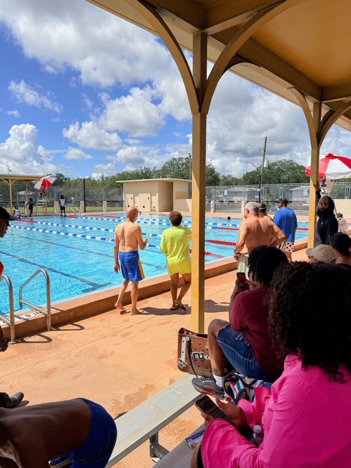 Families and spectators gathered poolside under the pavilion to cheer on swimmers